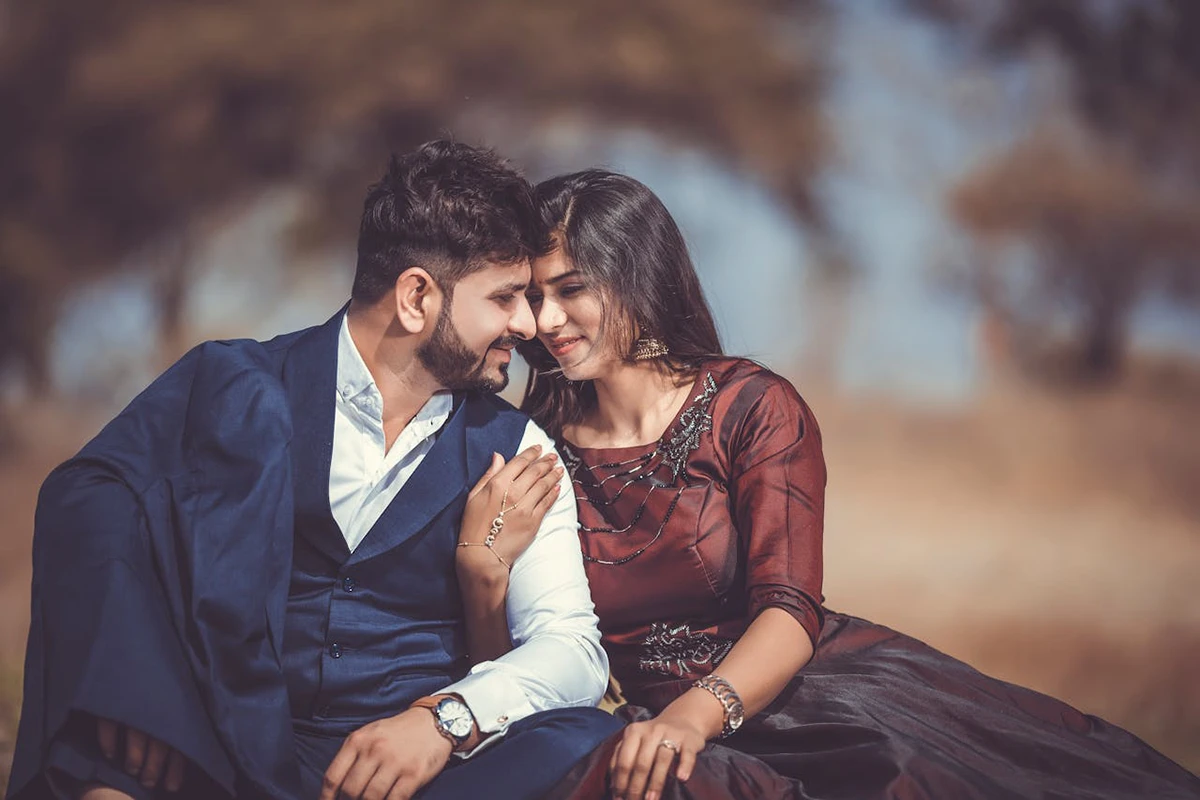 A couple sits close together outdoors, smiling and touching foreheads. Dressed for the occasion, they share a tender moment, reflecting the trust and harmony that couples seek when entering into a Binding Financial Agreement.
